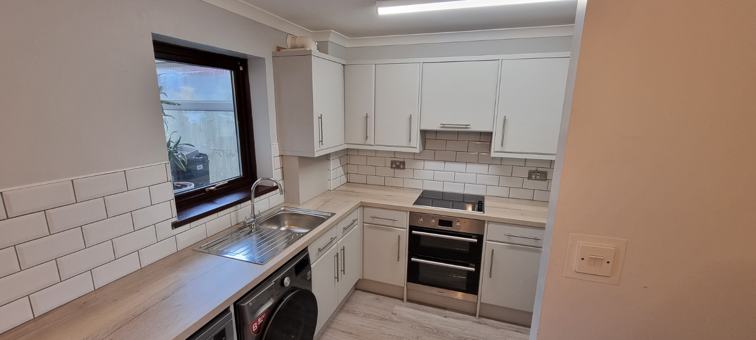 Finished kitchen viewed along the light wood-effect worktop towards the oven